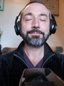 Image of Gram Davies with eyes closed, listening to someone in a telephone counselling session